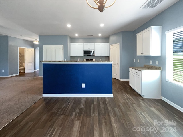 kitchen featuring dark colored carpet, a center island, and white cabinetry