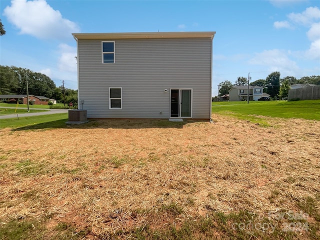 rear view of property featuring central AC unit and a yard