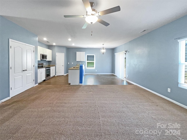 interior space featuring sink, ceiling fan, and dark colored carpet