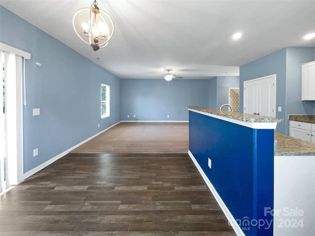 kitchen featuring dark hardwood / wood-style floors, ceiling fan with notable chandelier, white cabinetry, hanging light fixtures, and light stone countertops