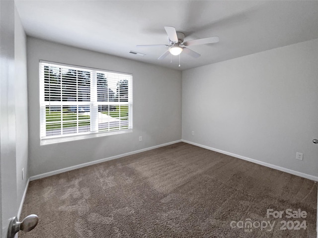 spare room with ceiling fan and dark carpet