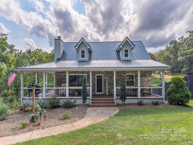 farmhouse featuring a front lawn and covered porch