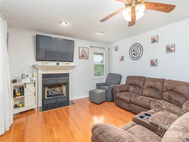 living room with ceiling fan, hardwood / wood-style flooring, and a tile fireplace