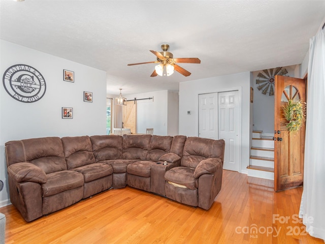 living room featuring ceiling fan, light hardwood / wood-style floors, and a barn door