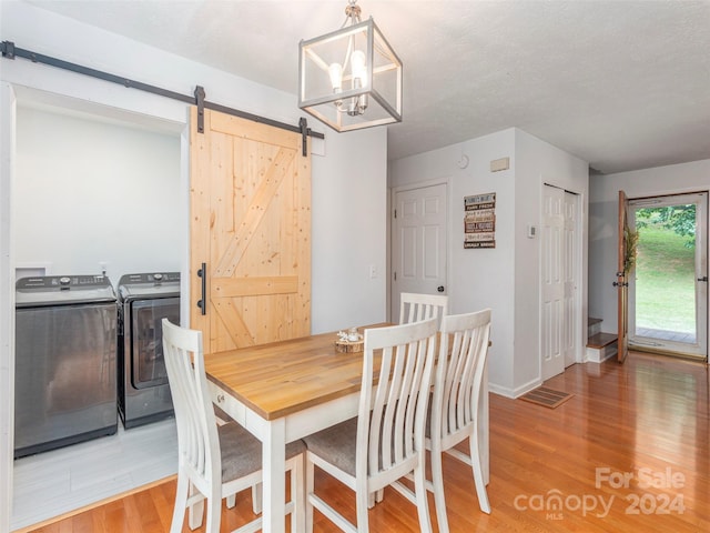 dining space featuring separate washer and dryer, a barn door, light hardwood / wood-style flooring, and a textured ceiling