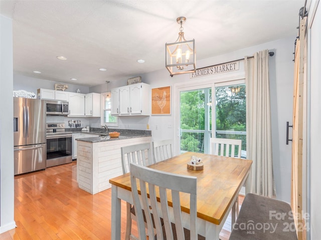 dining area featuring light wood-type flooring, sink, and a chandelier