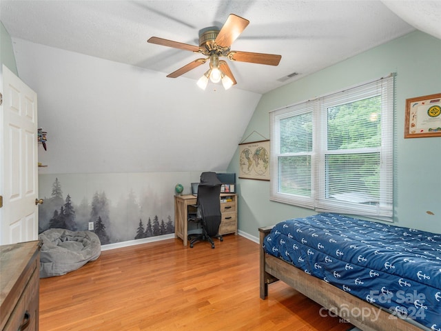 bedroom with hardwood / wood-style floors, vaulted ceiling, ceiling fan, and a textured ceiling