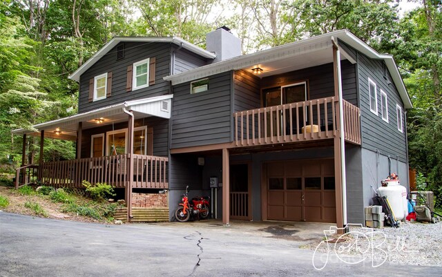 view of front of home featuring covered porch, a garage, and a balcony