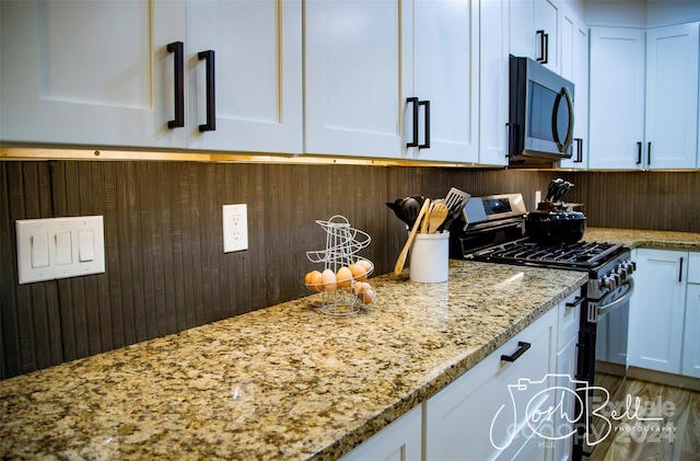 kitchen featuring stainless steel appliances, light stone countertops, and white cabinets