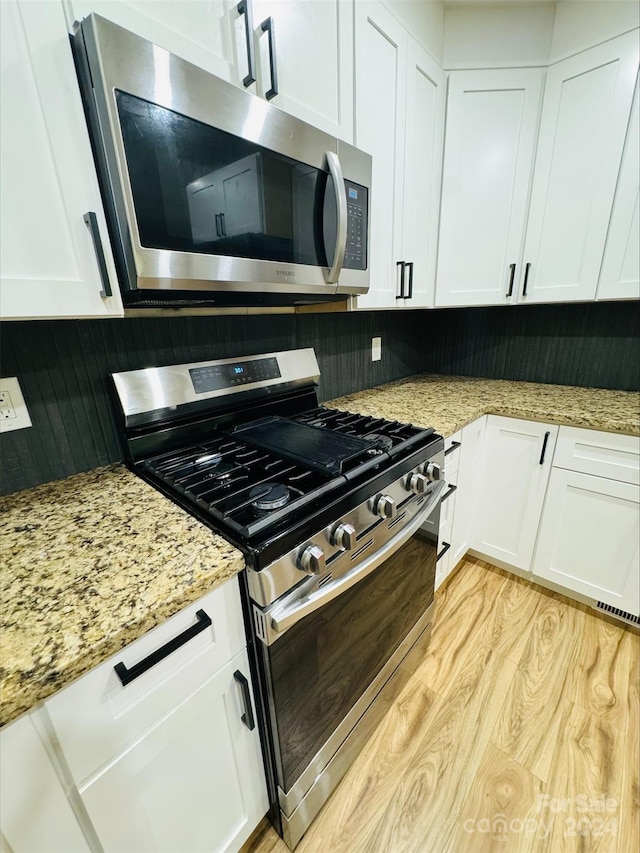 kitchen featuring light stone counters, backsplash, white cabinets, and appliances with stainless steel finishes