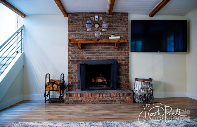 living room featuring beamed ceiling, wood-type flooring, and a fireplace