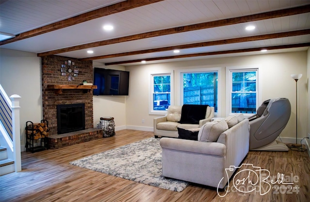 living room featuring a brick fireplace, light hardwood / wood-style flooring, and beamed ceiling