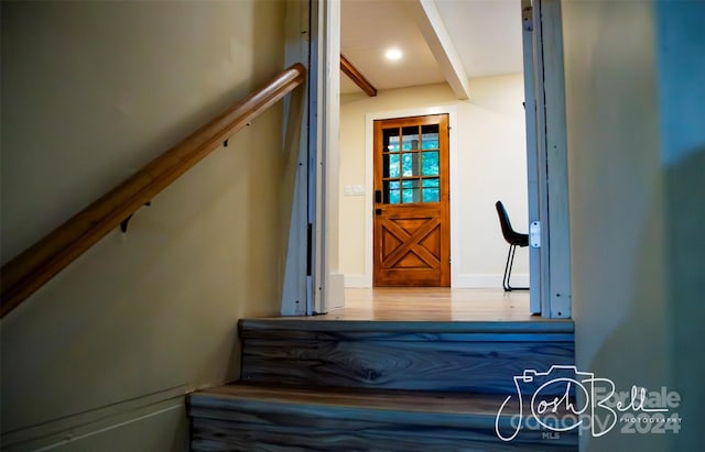 stairway featuring hardwood / wood-style flooring and beam ceiling