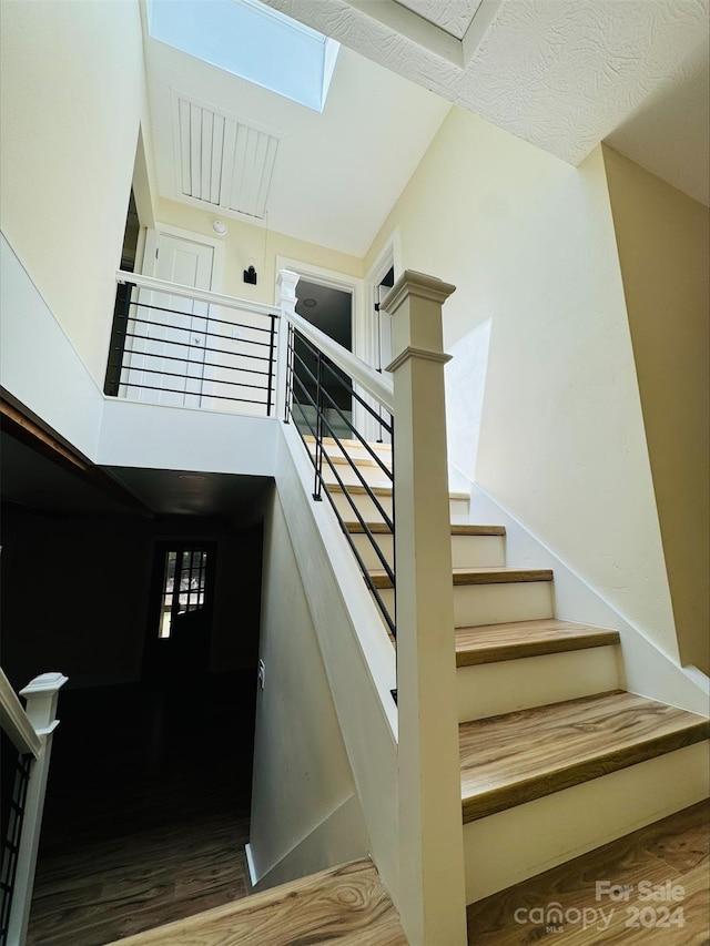 stairs with a towering ceiling and wood-type flooring