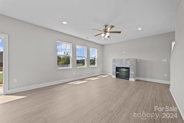 unfurnished living room with ceiling fan, light hardwood / wood-style flooring, and a high end fireplace