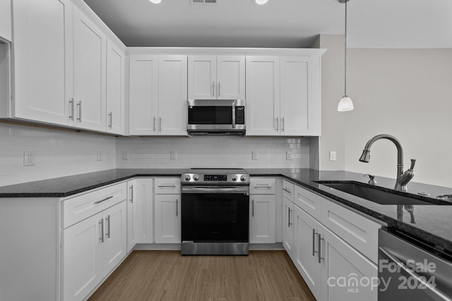 kitchen featuring stainless steel appliances, sink, wood-type flooring, decorative light fixtures, and white cabinets