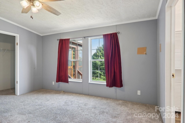 unfurnished bedroom featuring ceiling fan, crown molding, a textured ceiling, and carpet floors