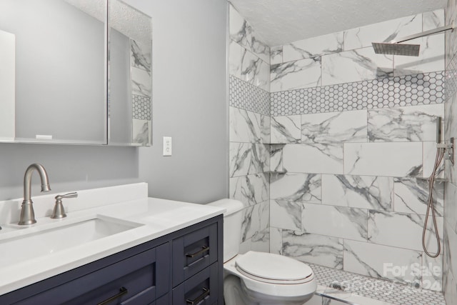 bathroom featuring tiled shower, toilet, a textured ceiling, and vanity