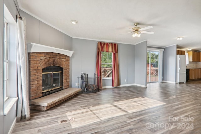 unfurnished living room with a wealth of natural light, a fireplace, hardwood / wood-style floors, and ornamental molding