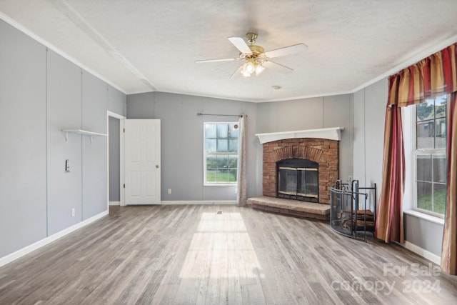 unfurnished living room with ceiling fan, lofted ceiling, wood-type flooring, and a brick fireplace