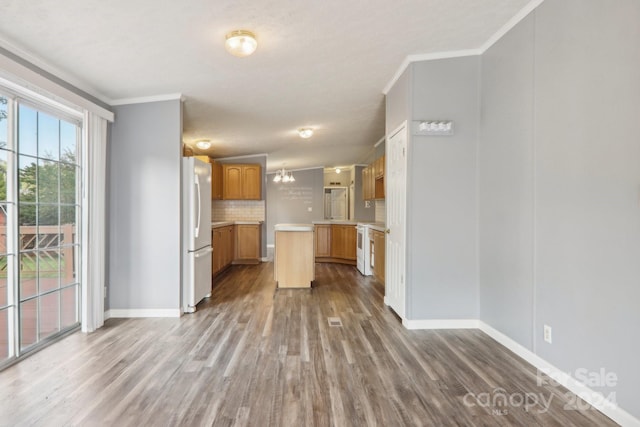 kitchen featuring backsplash, ornamental molding, hardwood / wood-style floors, and white fridge