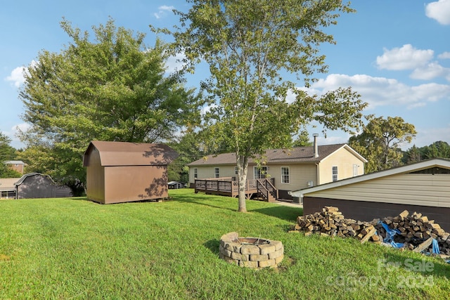 view of yard featuring a deck, a storage shed, and a fire pit