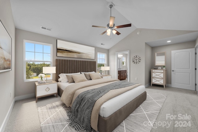 bedroom featuring ceiling fan, vaulted ceiling, light colored carpet, and ensuite bath