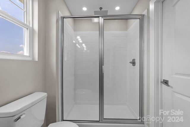 bathroom with toilet and a shower with door