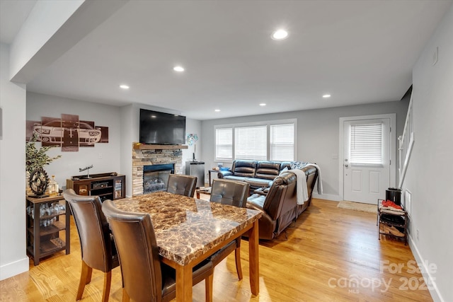 dining space featuring baseboards, a fireplace, light wood-style flooring, and recessed lighting