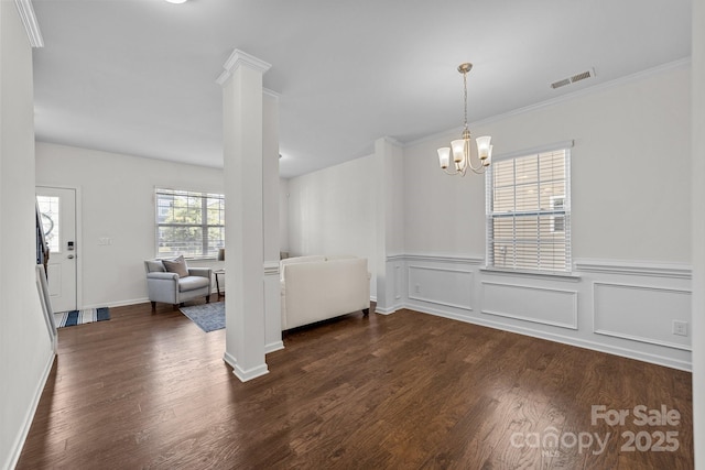 unfurnished dining area with dark hardwood / wood-style flooring, ornate columns, crown molding, and a chandelier