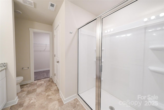 bathroom featuring a walk in closet, visible vents, a shower stall, and toilet