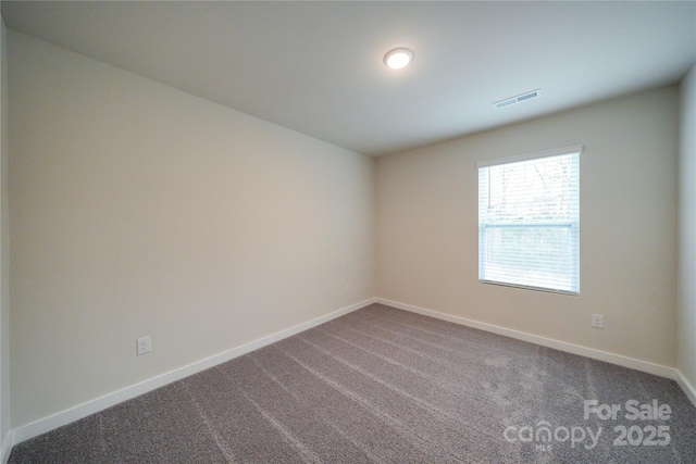 unfurnished room with carpet floors, visible vents, and baseboards