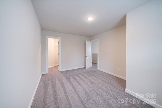 empty room featuring baseboards and light colored carpet