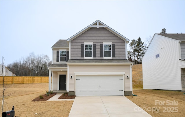 traditional-style home with an attached garage, fence, and concrete driveway