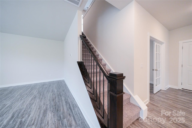 staircase featuring visible vents, baseboards, and wood finished floors