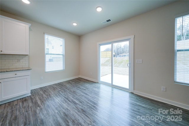 unfurnished dining area with recessed lighting, dark wood-style flooring, visible vents, and baseboards