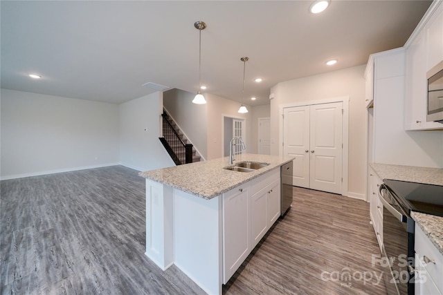 kitchen featuring stainless steel appliances, a kitchen island with sink, white cabinets, and a sink