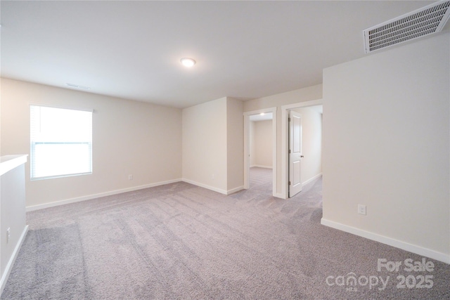 spare room featuring visible vents, light carpet, and baseboards