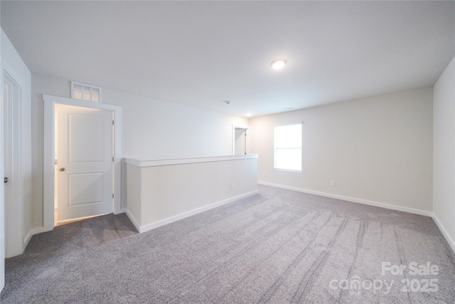 spare room with dark colored carpet, visible vents, and baseboards