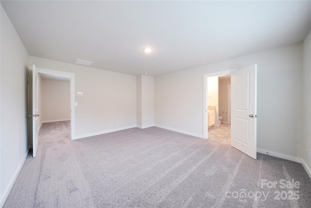 empty room featuring light carpet and baseboards