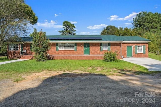 single story home with a front yard, roof mounted solar panels, brick siding, and metal roof