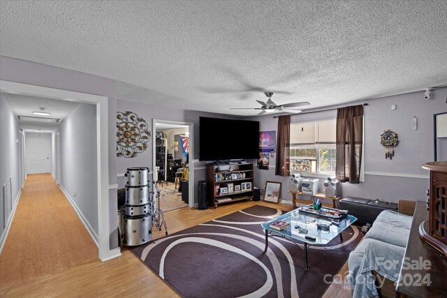 living room featuring a textured ceiling, light hardwood / wood-style flooring, and ceiling fan