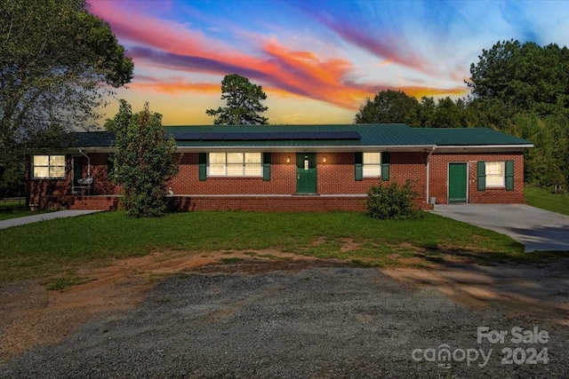 ranch-style house with metal roof, a front lawn, concrete driveway, and brick siding