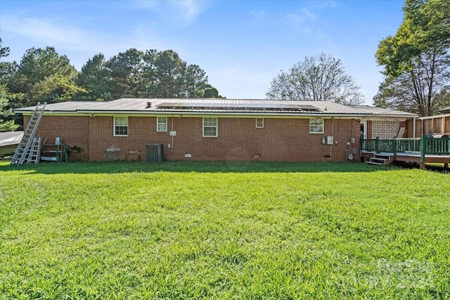 rear view of house featuring brick siding, a yard, a deck, and central air condition unit