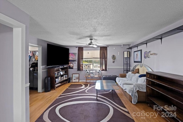 living room featuring ceiling fan, rail lighting, a textured ceiling, and light hardwood / wood-style floors