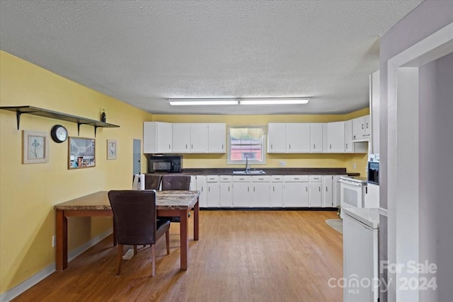 kitchen with black microwave, dark countertops, a sink, and white cabinets