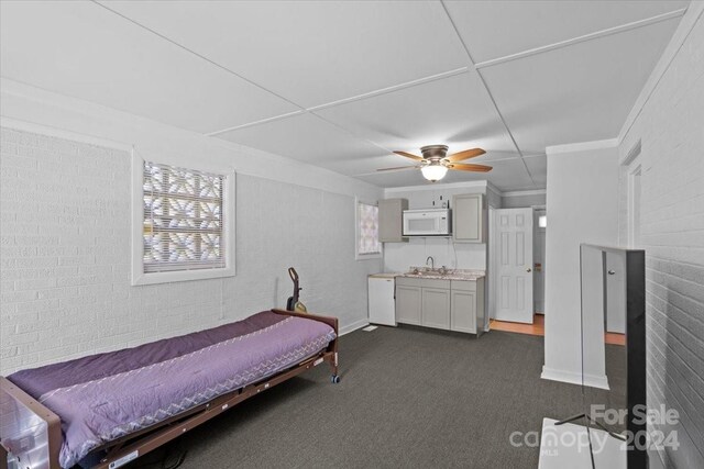 bedroom with dark colored carpet, ceiling fan, and sink