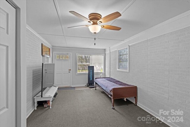 bedroom with ceiling fan, carpet, and brick wall