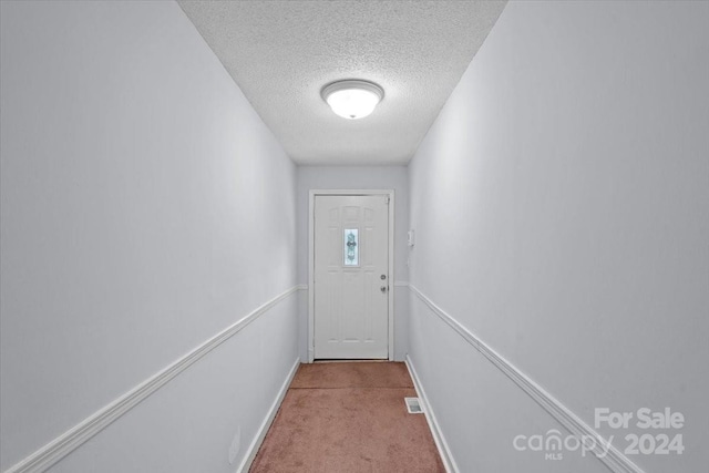 entryway featuring visible vents, light carpet, and a textured ceiling