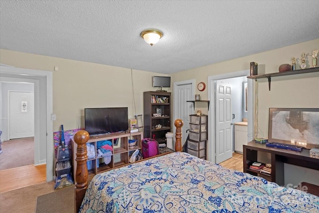 bedroom featuring a textured ceiling, light carpet, and connected bathroom